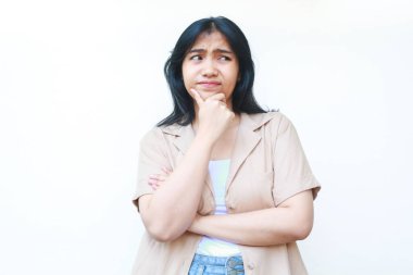 Düşünceli Asyalı kadın beyaz arka planda izole edilmiş günlük kahverengi kıyafetler giyiyor.