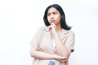 Düşünceli Asyalı kadın beyaz arka planda izole edilmiş günlük kahverengi kıyafetler giyiyor.