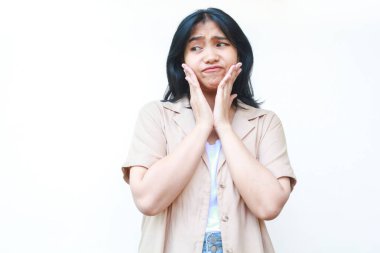Düşünceli Asyalı kadın beyaz arka planda izole edilmiş günlük kahverengi kıyafetler giyiyor.