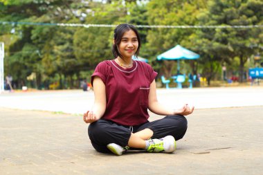 Mutlu Asyalı kadın voleybol sahasında yoga yapıyor.