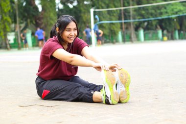 Mutlu Asyalı kadın voleybol sahasında yoga yapıyor.