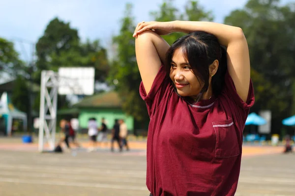 happy asian woman stretching hands in outdoor warm up before play basketball