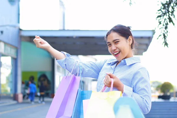 laughing asian woman holding shopping bag walking in outdoors