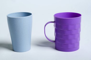 Beyaz arkaplanda izole edilmiş varyasyon şekilli mavi ve mor plastik bardak seti