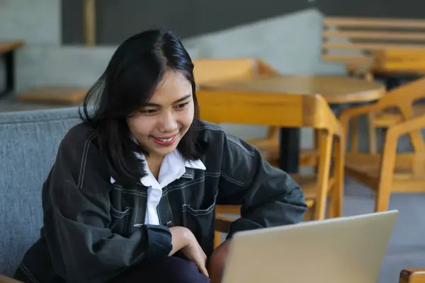 cheerful asian woman using laptop to have online meeting video conference in indoor cafe