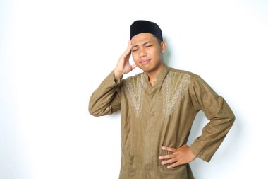 Koko kıyafeti giyen Asyalı müslüman, beyaz arka planda kendini yalnız hissederek başını tutuyor.