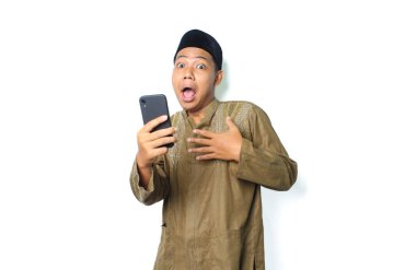 Asyalı Müslüman adamın cep telefonuyla göğsüne dokunması beyaz arka planda izole edilmiş şok edici bir ifade gösteriyor. Kameraya bakıyor.