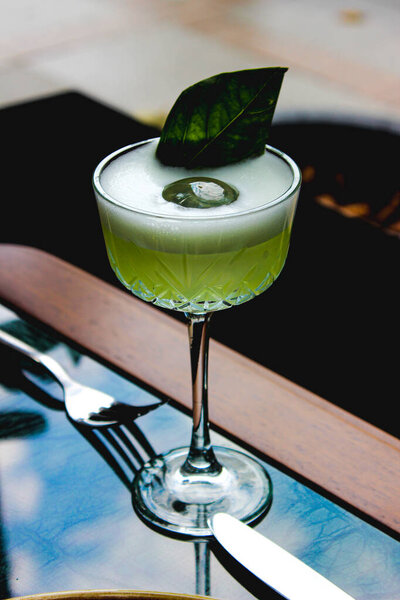 green cocktail with lime and mint on a wooden table