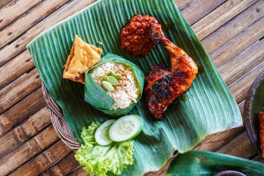 Kırmızı barbekü soslu ızgara tavuk, muz yapraklarıyla servis edilen sebze ve biber sosu.