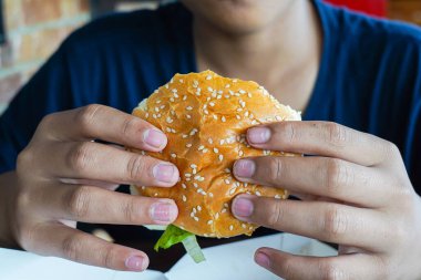 Bir çocuğun elinde hamburger, aç bir çocuk yemeden önce bir çizburger tutuyor, uzayı kopyalıyor.