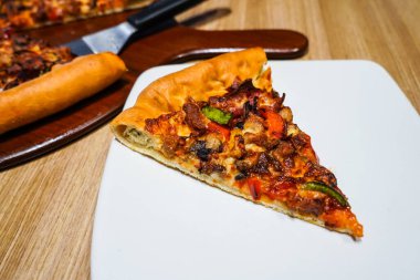 Taze İtalyan pizzası, mozzarella ve bol miktarda et malzemesi, beyaz tabakta.