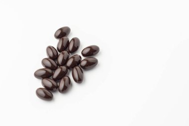 Beyaz zemin üzerinde siyah yumuşak jel kapsülleri, vitamin gıda takviyeleri, E vitamini diyet takviyesi