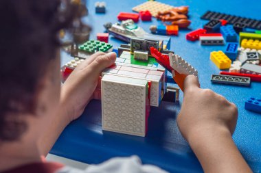 Çocukların erken yaşta öğrenme ve motor gelişimi, renkli plastik tuğlalarla oynayan ve inşa eden çocuk, eğitici yapı kavramı