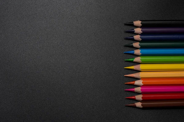 Set of colored pencils, row of wooden colored pencils on black background. colored pencils for drawing. pencils arranged in rainbow colors, colorful, copy space.