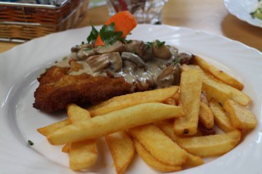 German cuisine: wiener schnitzel (cutlet) with mushroom sauce in Rudesheim am Rhein, Germany clipart