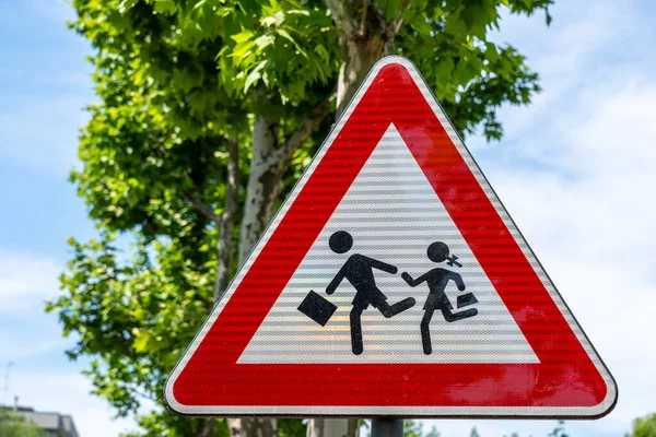 Çocuklar (okullar, çocuk parkları, bahçeler) tarafından sıklıkla ziyaret edilen yerleri duyuran uyarı işareti, arka planda bir ağaç ile
