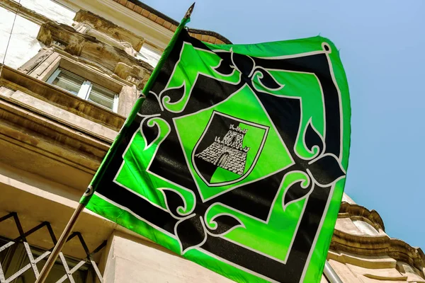 Bir direğe iliştirilmiş, merkezinde kale logosu olan eski yeşil ve siyah bir pankart Umbria 'da geleneksel bir palio sırasında dalgalanıyor.