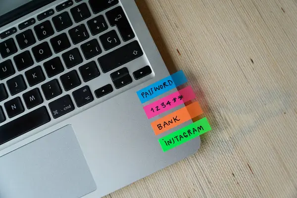 Areal view of a computer keyboard, featuring vibrant post-it notes as password reminders, set against a light wooden backdrop for added charm and clarity.
