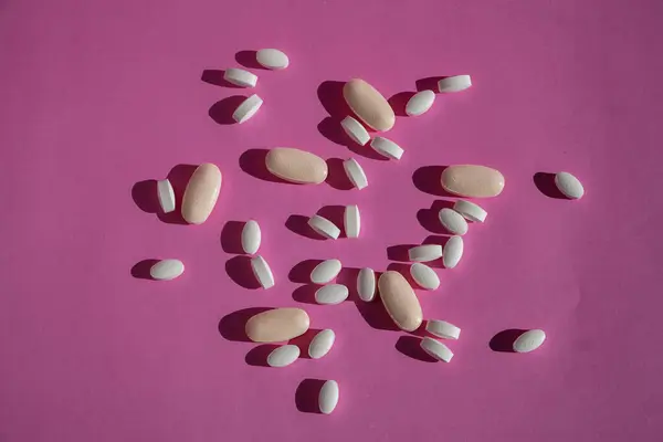 Pink surface covered with scattered pills.