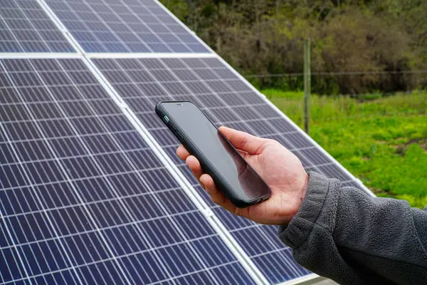 A person checking their phone with solar panels in the background.
