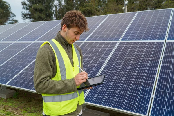 An engineer in uniform monitoring solar panels. Concept: sustainability, ecology, innovation.