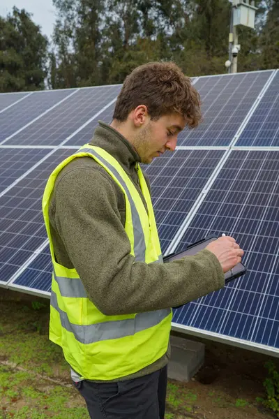 A young engineer monitoring solar panels for optimal performance.