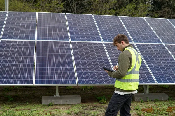 A uniformed professional working with solar panels in a forest in Chile.