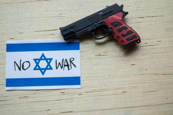 The Israeli flag is juxtaposed with a toy gun, presenting a powerful contrast between national symbolism and the themes of play and conflict.