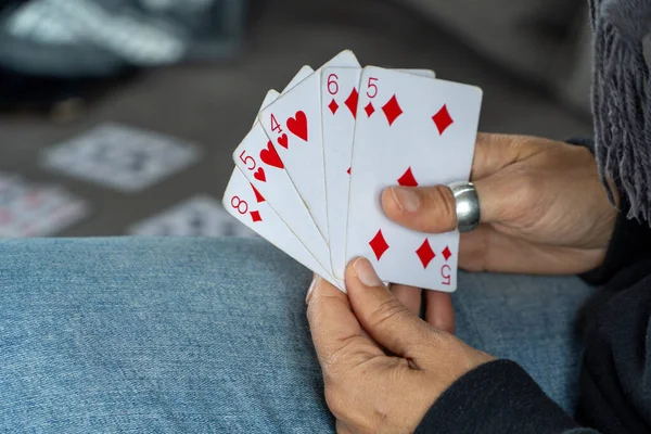 Woman\'s hands holding a deck of playing cards.