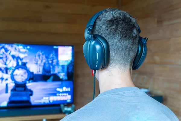 Teenager with gaming headphones playing video games at home.