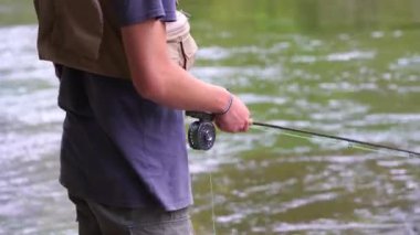 Genç adam nehirde balık tutuyor.