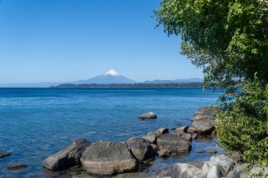 Summer view of a calm lake and a volcano in the back clipart