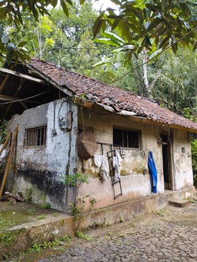 Bali Adası, 18 Mayıs 2023: Ormanda kahverengi çatılı ve Endonezya, Karangasem 'de asılı giysileri olan eski bir ev