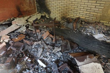 Yanmış molozlarla, kırık mobilyalarla ve kararmış duvarlarla dolu yangından zarar görmüş bir sınıf yıkımın sonucunu yansıtıyor..