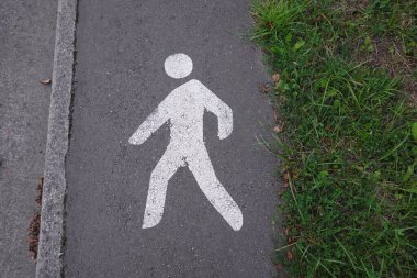 Asfalt yolda beyaz bir yaya sembolü çizilmiş, yayalar için belirlenmiş bir yürüyüş yolunu gösteriyor..