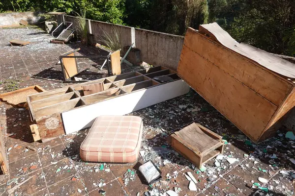 stock image An outdoor area in an abandoned school scattered with broken furniture, shattered glass, and debris, showcasing decay and neglect.