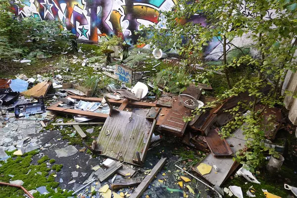 stock image An overgrown courtyard in an abandoned school, filled with broken furniture, shattered glass, and graffiti-covered walls, showcasing urban decay and nature's reclamation.