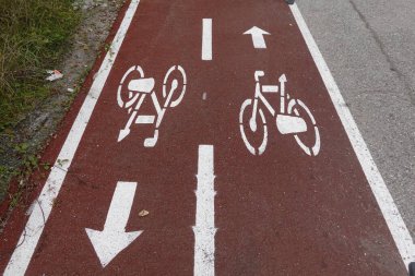 Kırmızı asfalt yolda bisiklet şeridi işaretleri ve iki yönlü bisiklet trafiğini gösteren yön okları..