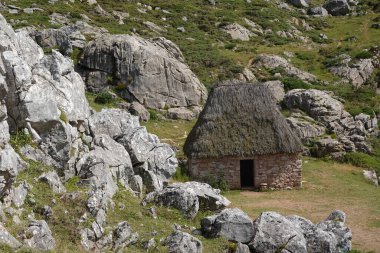 Teito olarak bilinen sazdan çatılı, kayalık arazi ve çimenli tepelerle çevrili geleneksel taş kulübe..