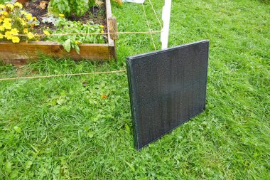 Küçük projeler veya cihazlar için sürdürülebilir enerji sağlayan taşınabilir güneş paneli bahçede şarj ediliyor