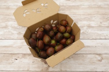 Olgun kivi üzümleri (Hardy kiwi (Actinidia arguta), pazar veya tüketime hazır sürdürülebilir bir karton kutuyu doldurur.