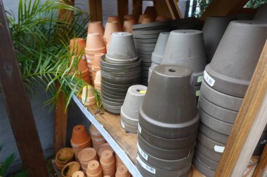 Birçok terracotta ve plastik saksı bir bahçe merkezinde veya bitki yetiştirme odasında müşterileri bekliyor.