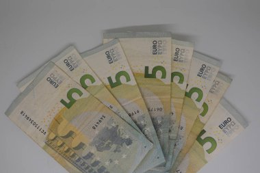 Beş avroluk birkaç banknot, para biriminin tasarım ve güvenlik özelliklerini basit bir beyaz fon üzerinde sergileyen bir yarım daire şeklinde düzenleniyor.
