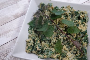 Çırpılmış yumurta ve taze ısırgan otu, besin değeri yüksek ve canlı yeşil bir yemek sunar.