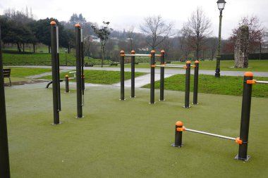 Modern egzersiz ekipmanları yeşil bir parkta kullanılmaya hazır. Sağlıklı yaşam tarzlarını ve açık hava sporlarını destekliyor.