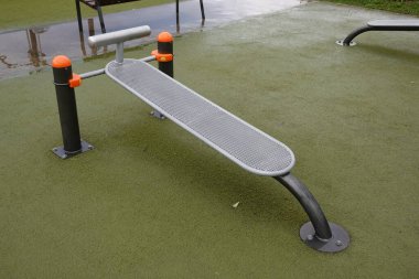 Yağmurdan sonra halka açık bir parkta boş bir oturma tezgahı, spor ve açık hava egzersizlerini destekliyor.