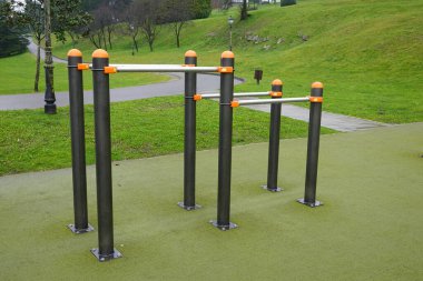 Paralel barlar ve diğer egzersiz ekipmanları yeşil bir parkta kullanılmaya hazır, sağlıklı yaşam tarzları ve açık hava sporları teşvik ediliyor.