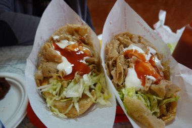 İki pide kebabı traş edilmiş et, marul, kremalı yoğurt sosu ve baharatlı acı sosla doldurulur.