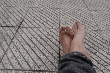 Ayaklar dokulu bir kaldırımda dinleniyor, yaz tatili boyunca bir anlık rahatlığın tadını çıkarıyor.