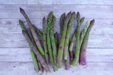 Taze biçilmiş yeşil kuşkonmaz mızrakları, canlı renkler ve doğal dokular sergiliyor.